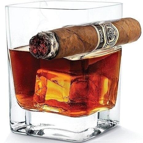 Verre à whisky porte-cigare carré avec cigare posé sur le repose-cigare latéral et whisky sur glace